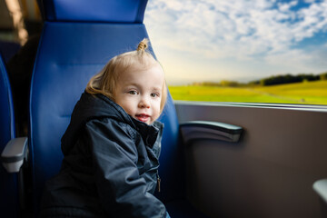 Toddler boy traveling by train. Little child sitting by the window in express train on family vacation. Kid in a railroad car. Going on vacation with kids.