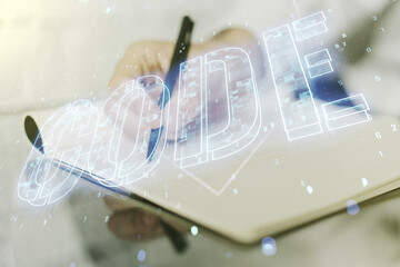 Poster - Creative Code word hologram and man hand writing in notepad on background, artificial intelligence and neural networks concept. Multiexposure