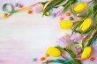 Yellow and purple tulips, candy eggs, rainbow ribbon on colorful watercolor paper. Easter card, copy space.