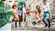 Happy multiracial people jumping together outdoors on city street - Group of young people enjoying freedom together - Friendship concept with group of youth friends from diverse cultures having fun .