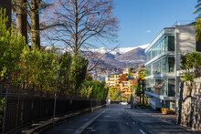 View On Street Of Lugano And Snowcapped Mountains Behind