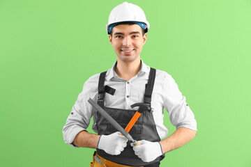 Canvas Print - Young carpenter with file and hammer on green background