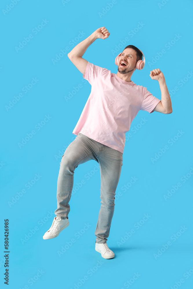Handsome man in headphones dancing on blue background