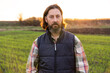 Portrait of bearded farmer on a field at sunset.