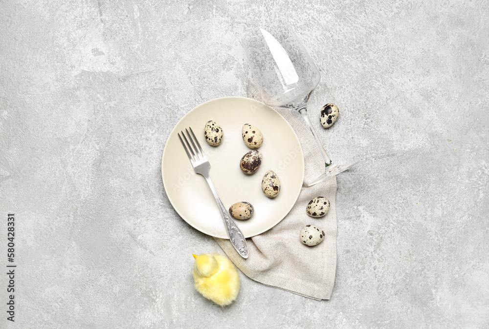 Table setting with baby chicken, wine glass, fork and quail eggs on grey grunge background