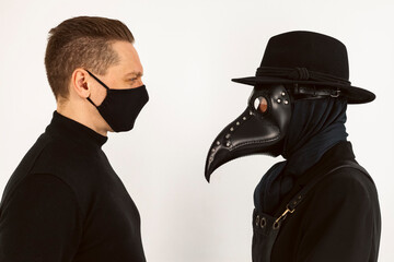 Wall Mural - A Plague doctor and a man in a Medical mask looking at each other. a syringe and needle with Medicine or serum, antidote. Isolated on a white background. COVID-19, epidemic and pandemic concept.