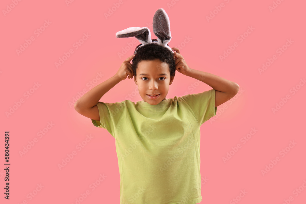 African-American little boy in bunny ears on pink background