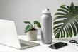 Front view of a white desk with a grey insulated bottle, modern technology, and a plant. Generative AI