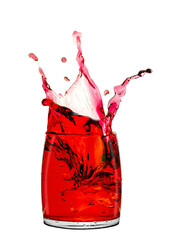 Wall Mural - Splashes of red drink in transparent glass close-up isolated on white background