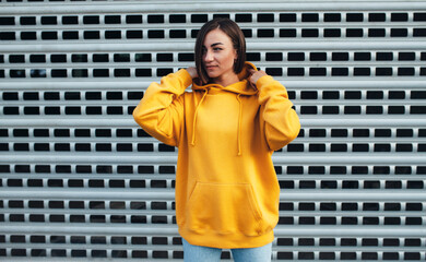 Wall Mural - Handsome young female wearing yellow blank hoodie with space for your logo or design. Mockup for print