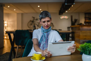 Wall Mural - One woman mature adult senior female use digital tablet at cafe