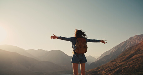 young girl standing on top of mountain and victoriously raising hands up, looking far away - zennism