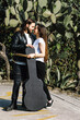 young hispanic couple man and woman in rock and roll style walking and playing guitar in the street in Mexico Latin America