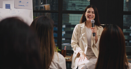 confident young businesswoman or speaker sharing ideas with colleagues or audience during company se