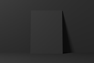 Empty blank black poster leaning on a black wall.