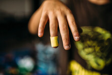 Cropped Image Of Boy Showing Bandage On Finger At Home