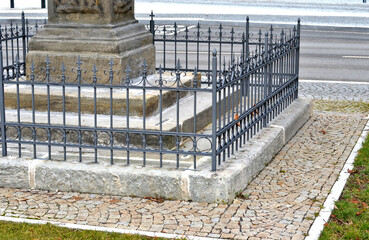 fencing with ornamental trellises and flowers forged by a blacksmith. the surrounding area is separated from the sacred ground of the grave with the help of spikes.