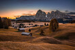 Alpe di Siusi, Italy - Seiser Alm, an alpine meadow on a warm autumn sunrise with Saslonch (Sassolungo or Langkofel) mountain of the Italian Dolomites and wooden cottages and colorful sky and clouds