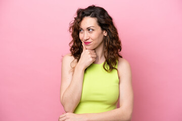 Wall Mural - Young caucasian woman isolated on pink background looking to the side and smiling