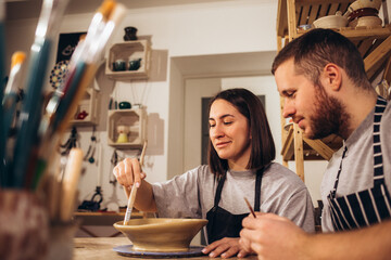 A happy young couple paints dishes at a pottery class