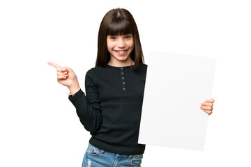 Little girl over isolated chroma key background holding an empty placard and pointing side