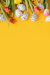 beautiful easter layout with tulips and painted eggs on bright yellow background. top view. copy spa