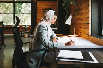 Wall Mural - Muslim designer working on architectural blueprints in an office