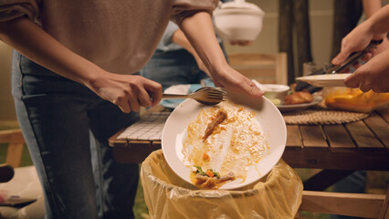 Group of people party at home after meal eating throw away leftovers food to plastic bag junk trash bin. Net zero waste go green eco friendly lifestyle reduce household scrap. Save the planet earth.