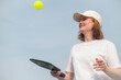 middle aged woman playing pickleball game over blue sky, pickleball yellow ball with paddle, outdoor sport leisure activity