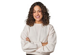 Radiant young woman with stunning curls who feels confident, crossing arms with determination.