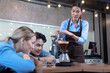 © Basicdog - Male and female students learn to brew coffee in barista school.