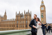 Happy Couple Of Young Travelers Embrace Against The Background Of London's Big Ben