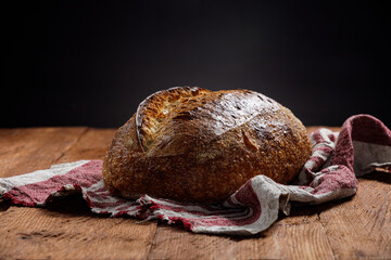 Fototapete - Rustic sourdough bread on a linen towel on a wooden background