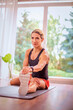 © gzorgz - Woman sitting on a yoga mat and stretching at home after workout