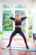 © gzorgz - Mid aged woman exercising with a power band at home