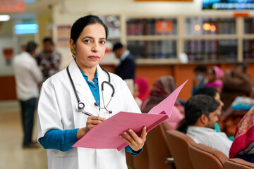 Wall Mural - Indian female doctor writing medical record in file.