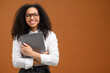 Nice pretty African american female student or coworker holding clutching laptop in anticipation new job or interesting tasks and smiling, female office employee in formal wear isolated on brown
