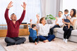 © Tongpool - The family have fun relax engaged in fitness yoga at home using online instruction from laptop