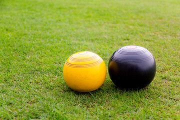 Wall Mural - Crown green bowling ball, up against the yellow Jack on green, as competition takes place outdoors.