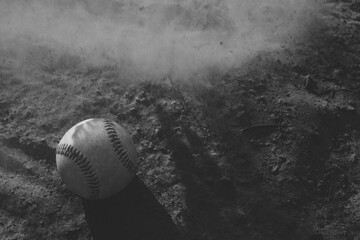 Poster - Baseball game concept during summer sports season with dirt in motion over ball on field in black and white, copy space on background.