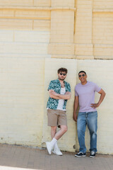Wall Mural - multiethnic friends in sunglasses posing near building on street in kyiv.