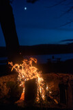 Fototapeta Nowy Jork - A campfire on Taylor Pond in the Adirondack mountains with a slight illuminatio of the moon