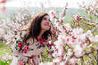 woman sniffs pink flowering trees in peach garden nature spring