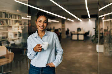 Wall Mural - Happy African businesswoman taking a break after hard work at the office.