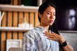 © bnenin - A focused Asian woman practicing breathing techniques in the early morning at home.