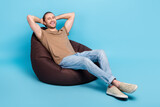 Fototapeta Panele - Full length photo of dreamy cheerful man wear beige t-shirt bean bag arms behind head emtpy space isolated blue color background