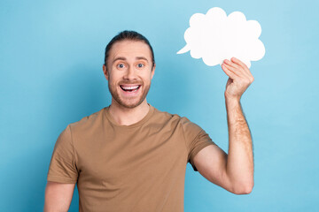 Wall Mural - Photo of positive impressed man tail hairdo dressed beige t-shirt holding mind cloud empty space isolated on blue color background