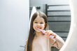© inna717 - Happy little girl brushing her teeth in front of a bathroom mirror. Morning hygiene.