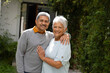 © Wavebreak Media - Portrait of loving biracial senior couple smiling and standing by lush ivy growing outside house