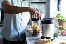 Midsection Of Biracial Senior Man Blending Fruits And Making Healthy Smoothie On Kitchen Counter